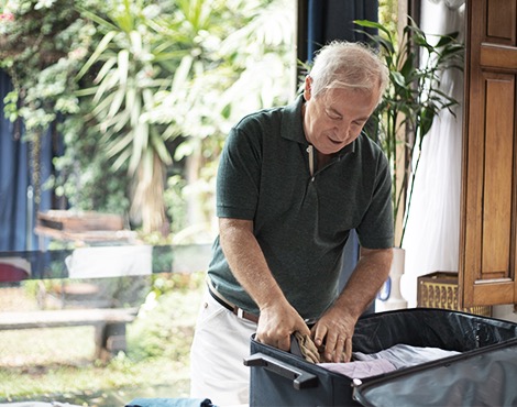 Man happily packing a suitcase while preparing for a trip